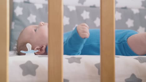 niño pequeño molesta piernas descalzas acostado en cama de bebé de cerca