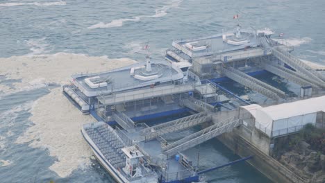 The-Wide-Industrial-Plant-Above-The-Deep-Ocean-In-Niagara-Canada-Surrounded-With-Big-Waves-During-Daytime---Aerial-Shot