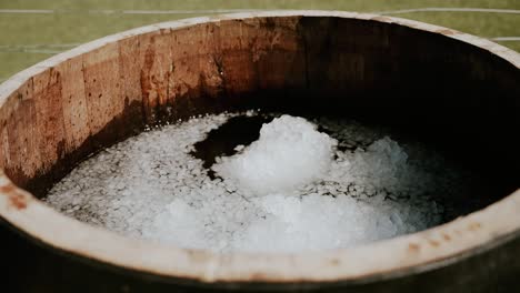 Agua-Helada-En-Barril-De-Madera,-Tiro-Hacia-Atrás