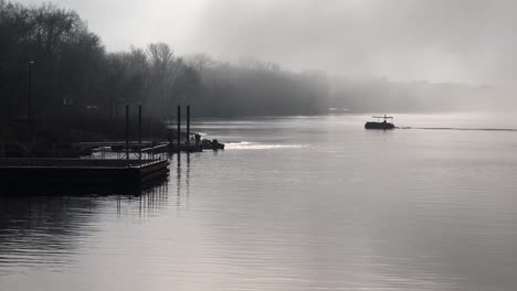 fishing boats head out on a foggy morning along the mississippi river