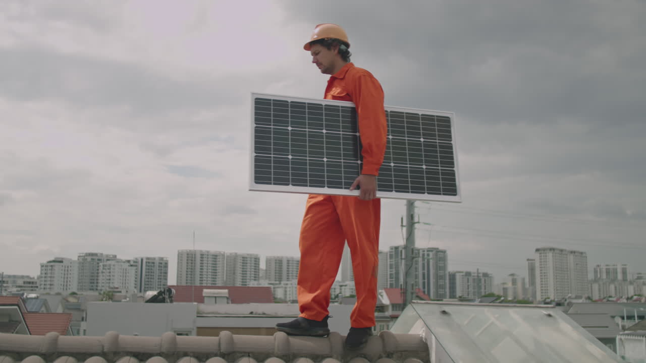 Worker Walking on Rooftop and Carrying Solar Panel