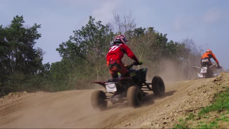 quad bike riders jump over a hill during tournament