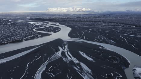 aerial flyover glacial river named sula flowing between black volcanic landscape in iceland