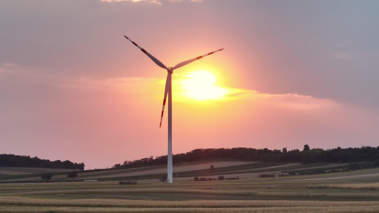 태양이 지평선에 서는 동안 회전하는 풍력 터빈은 재생 가능한 에너지의 아름다움을 선보이며 자연의 황혼의 빛과 완벽하게 혼합됩니다.