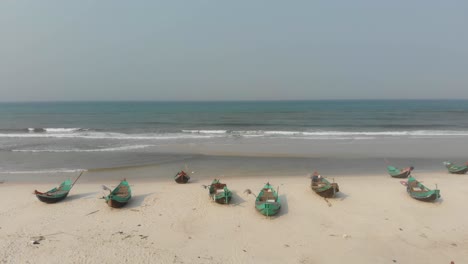 Flying-backwards-at-Trung-Thanh-Beach-Vietnam-with-fishing-boats,-aerial