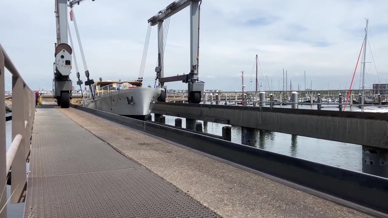 Industriekran, der eine Yacht von einem erhöhten Standpunkt aus in den Hafen absenkt.