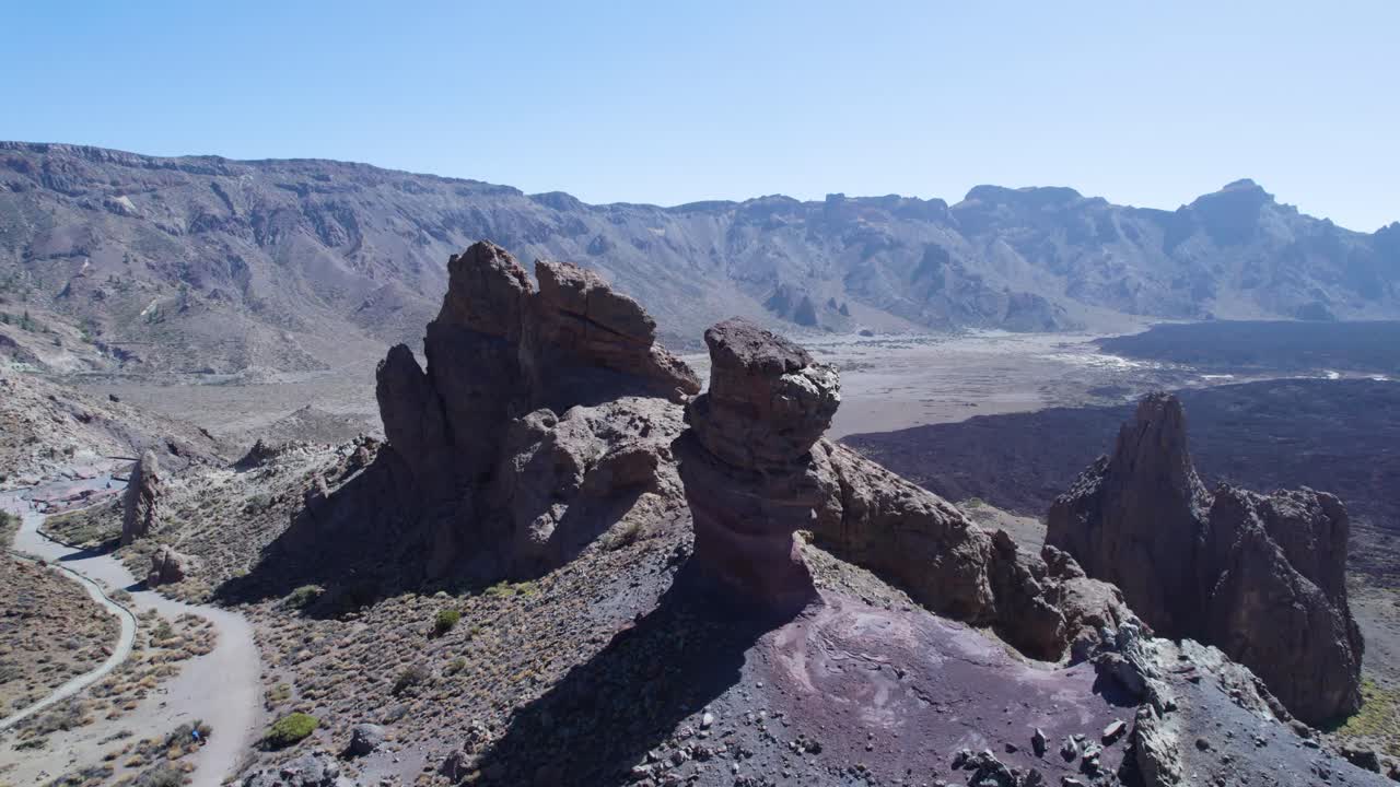 Filmato aereo realizzato con drone che vola all'indietro per rivelare le iconiche formazioni rocciose di Roques de García all'interno del Parco nazionale del Teide a Tenerife, in Spagna, ampiamente utilizzato per riprese di viaggio e ambientazione.