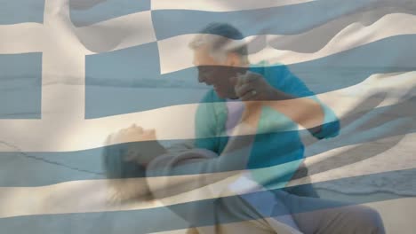 animación de la bandera de grecia sobre una feliz pareja caucásica mayor bailando en la playa