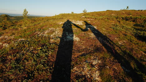 las sombras de dos viajeros caminan por el terreno montañoso tomados de la mano estilo de vida activo