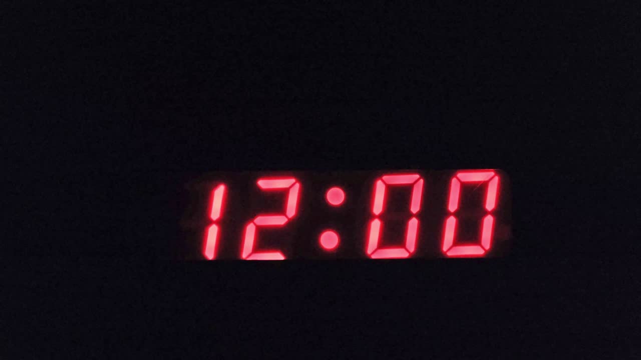 Modern digital clock numbers flashing midnight on and off. Black background