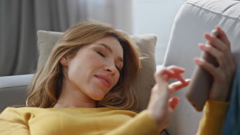 happy lady laying sofa messaging mobile phone closeup. carefree woman chilling
