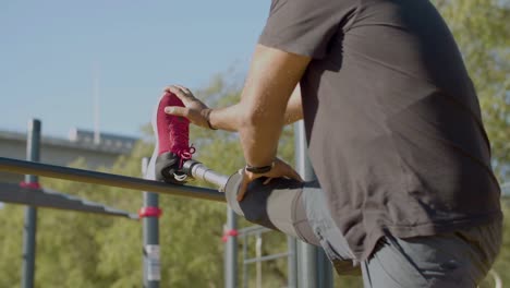 Side-view-shot-of-man-with-prosthesis-doing-stretching-exercise.