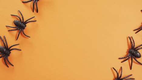 Close-up-of-multiple-spider-toys-with-copy-space-against-orange-background