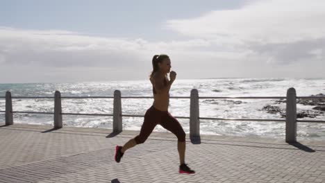 Sporty-Caucasian-woman-exercising-on-a-promenade-on-seaside