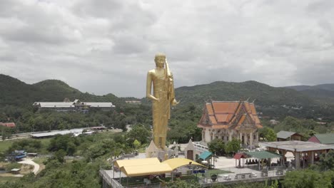 huge golden buddha statue standing on hilltop next to wat khao noi , orbiting shot