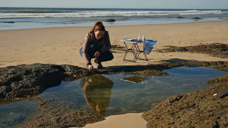 woman conducting research at a tide pool on a sunny beach