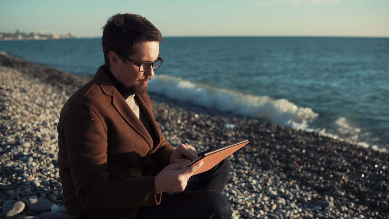 hombre usando tableta en la playa