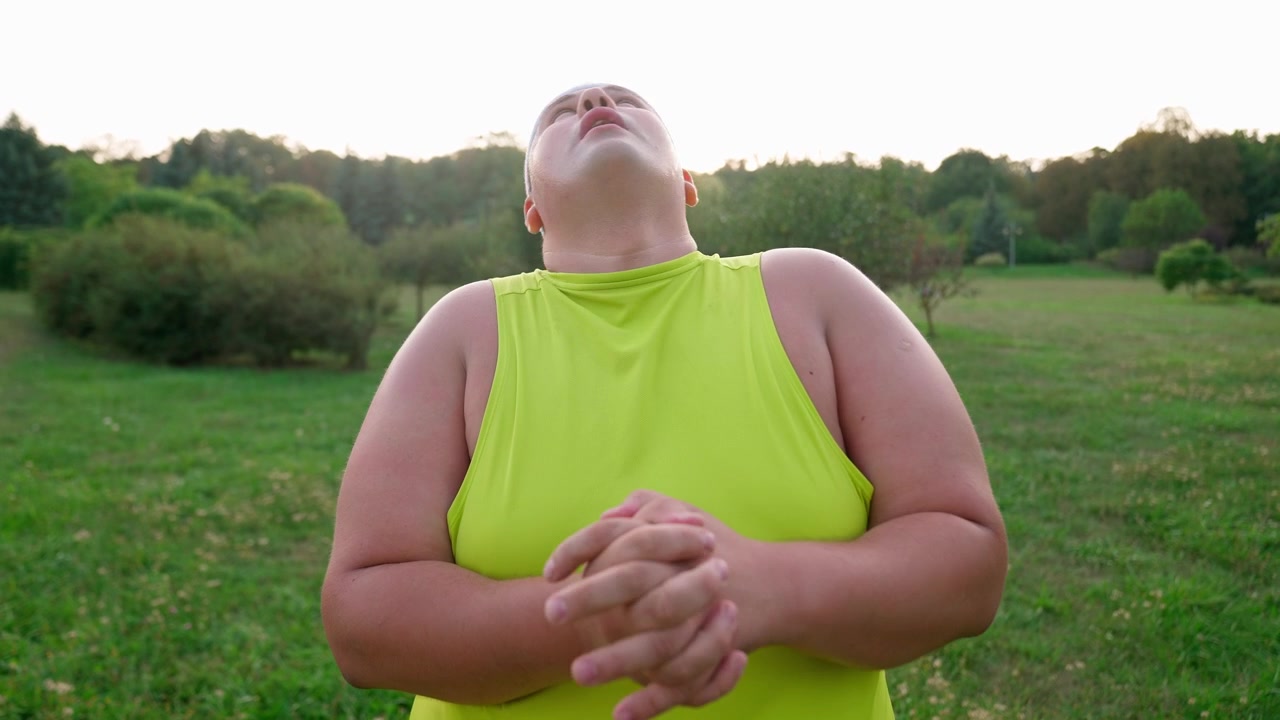Uomo in sovrappeso che allunga il collo durante il riscaldamento all'aperto nel parco