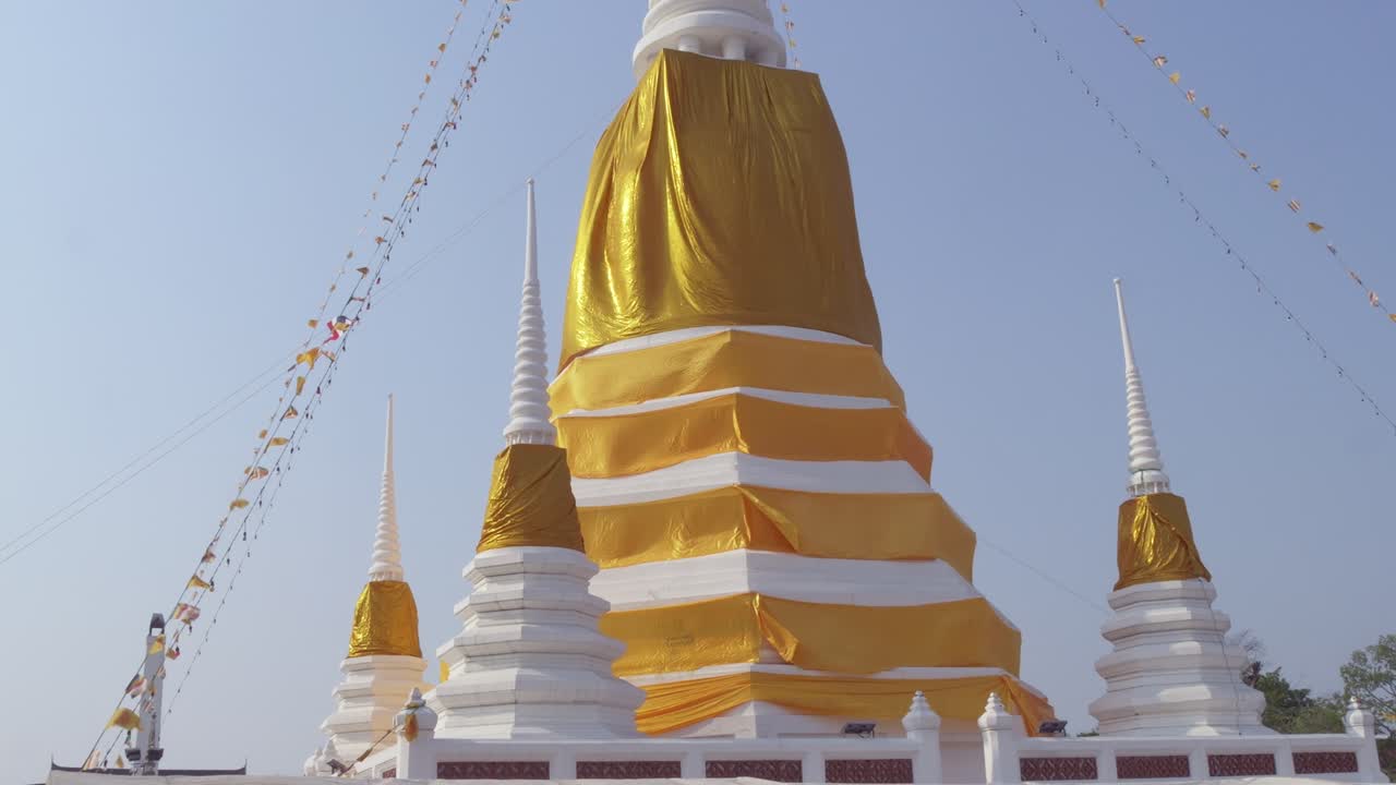 Witness the vibrant golden stupa adorned in ceremonial silk during a sacred festival in Thailand.