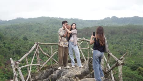 young asian indonesian friends taking photo on mountain viewpoint with phone, nature travel