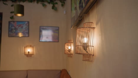 close up of glowing light bulb enclosed in vertical wooden decorative frame on softly lit wall with blurred background showing additional lamps and television
