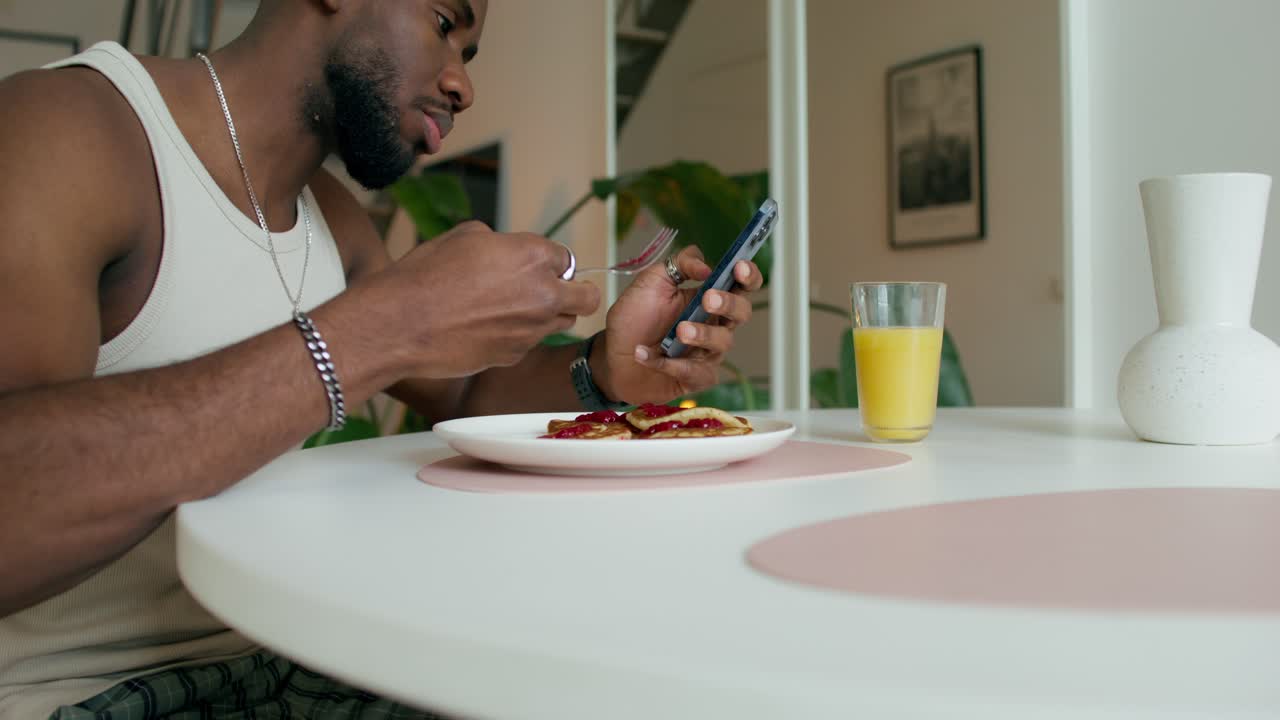 hombre comiendo panqueques y tomando una foto con su teléfono