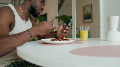 man eating pancakes and taking a picture with his phone