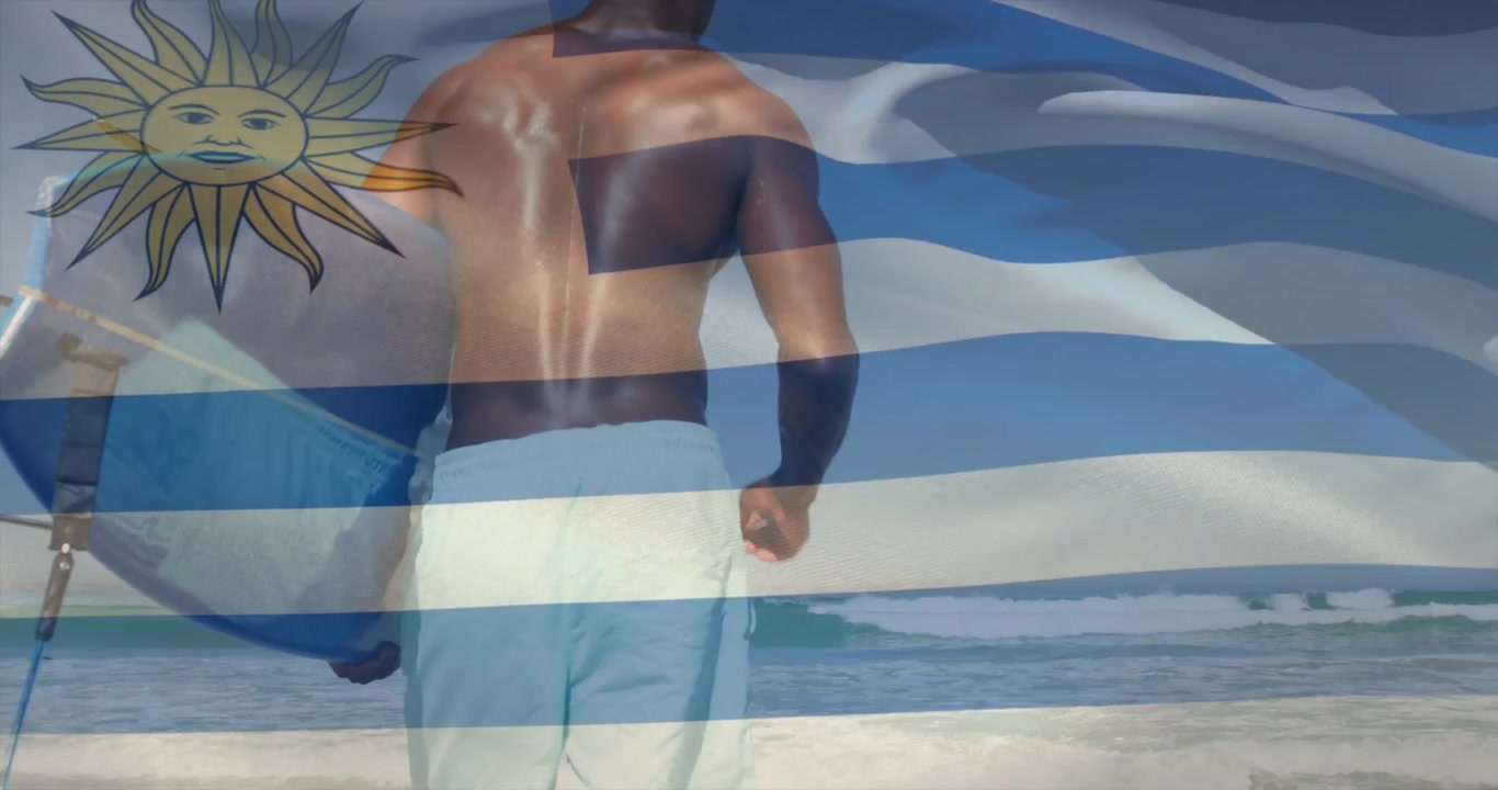 Surfer mit Surfbrett betritt die Brandung, während Wellen locken, mit einer über die Szene wehenden Uruguay-Flagge als Überlagerung.