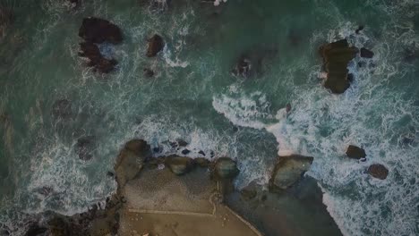 Cenital-Clip,-Der-Mehrere-Felsen-Zeigt,-Die-Während-Eines-Sonnenuntergangs-An-Einem-Felsigen-Strand-Von-Wellen-Getroffen-Werden