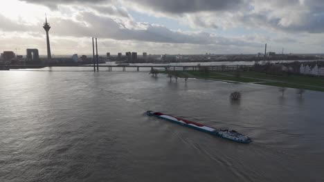 Vista-Por-Drones-De-Una-Barcaza-Navegando-Por-El-Río-Rhein,-Dusseldorf,-Alemania