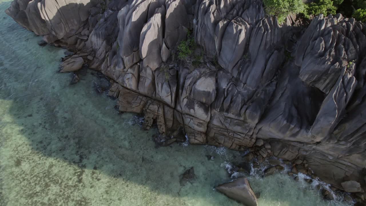 Maestose riprese con drone di massi di granito unici che incontrano acque turchesi e giungla lussureggiante ad Anse Grosse Roche, La Digue 011 30fps.