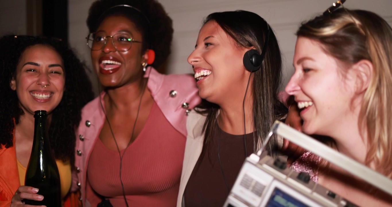 Donne multietniche felici che ridono e ascoltano musica a una festa