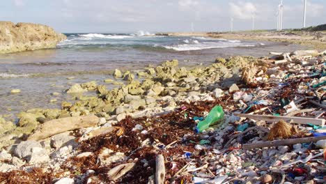 wide tilt up of plastic trash debris littered on rocky beach in caribbean