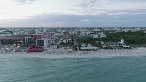 aerial drone dolly in view of a cityscape by the coast, with built structures, rolling clouds and endless horizon in playa del carmen, mexico