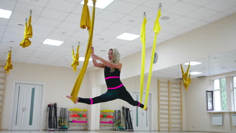 young beautiful yogi woman doing aerial yoga practice in purple hammock in fitness club