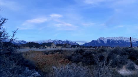 Cañón-Pequeño-Y-Escarpado-En-El-Borde-De-Un-Barrio-Suburbano-Con-Montañas-Cubiertas-De-Nieve-Con-Vistas-A-La-Comunidad-Del-Valle---Lapso-De-Tiempo-Panorámico