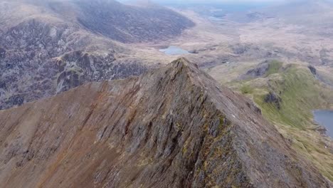 drone captures the majestic sharp crib goch mountain from aerial perspective, revealing its rugged ridges and dramatic peaks against vast open landscape at snowdonia national park, wales