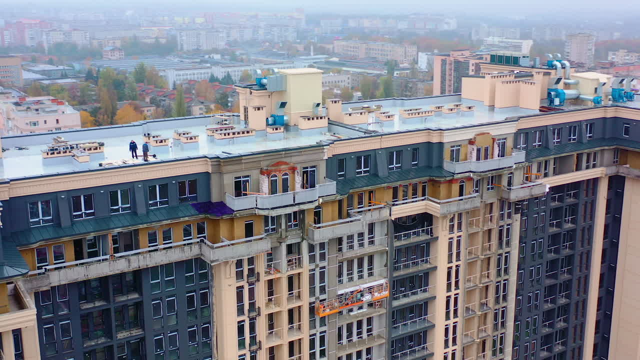 Construction site in the city. Modern architecture is building by workers. High-rise building under construction. Camera moves in a round way. Aerial view.