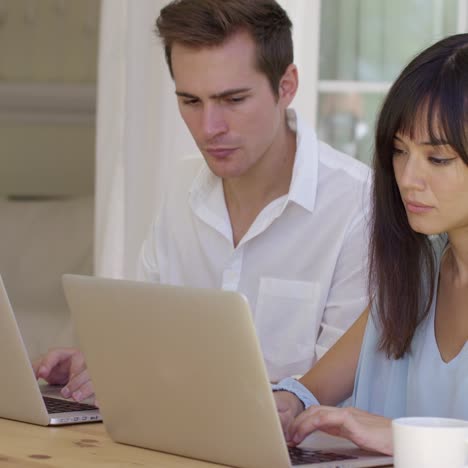 hombre y mujer trabajando juntos en computadoras portátiles