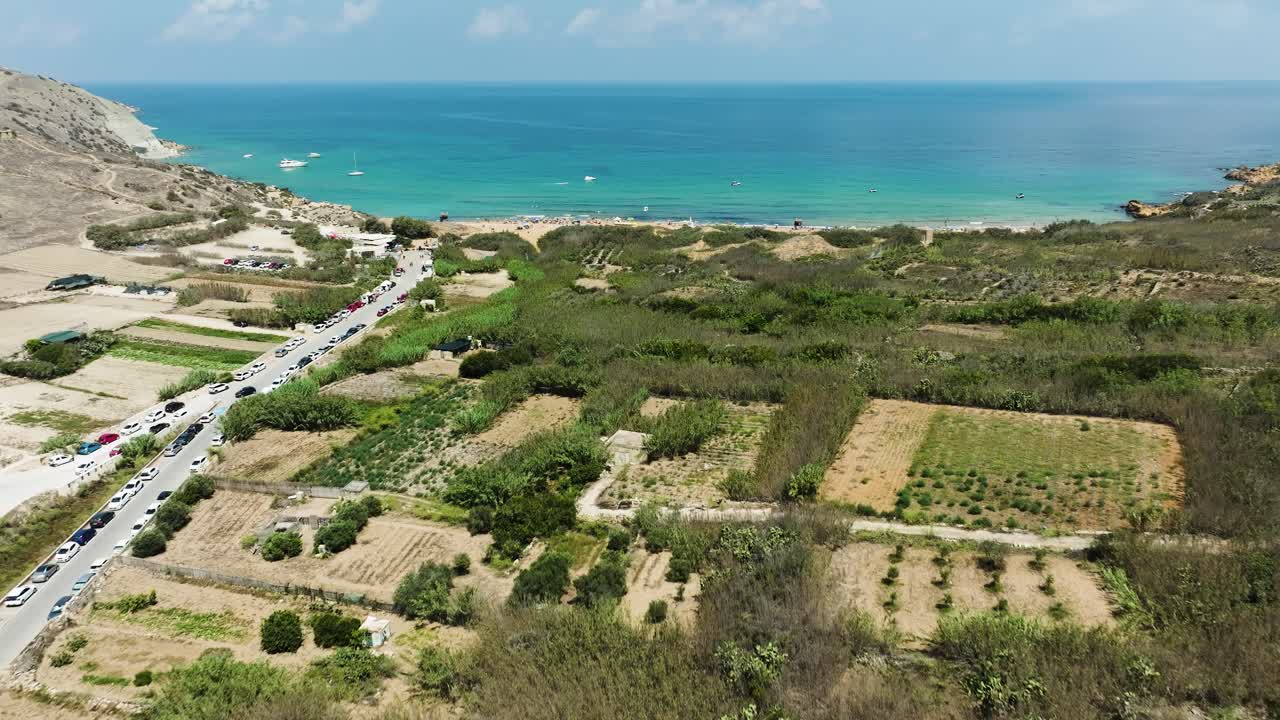 las imágenes de drones capturan una serena vista aérea de una playa prístina, con vibrantes aguas azules del océano y el campo en el fondo