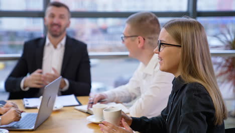 team in the office having discussion in friendly atmosphere. people sitting at the table and having a talk and drinking coffee. blurred backdrop.