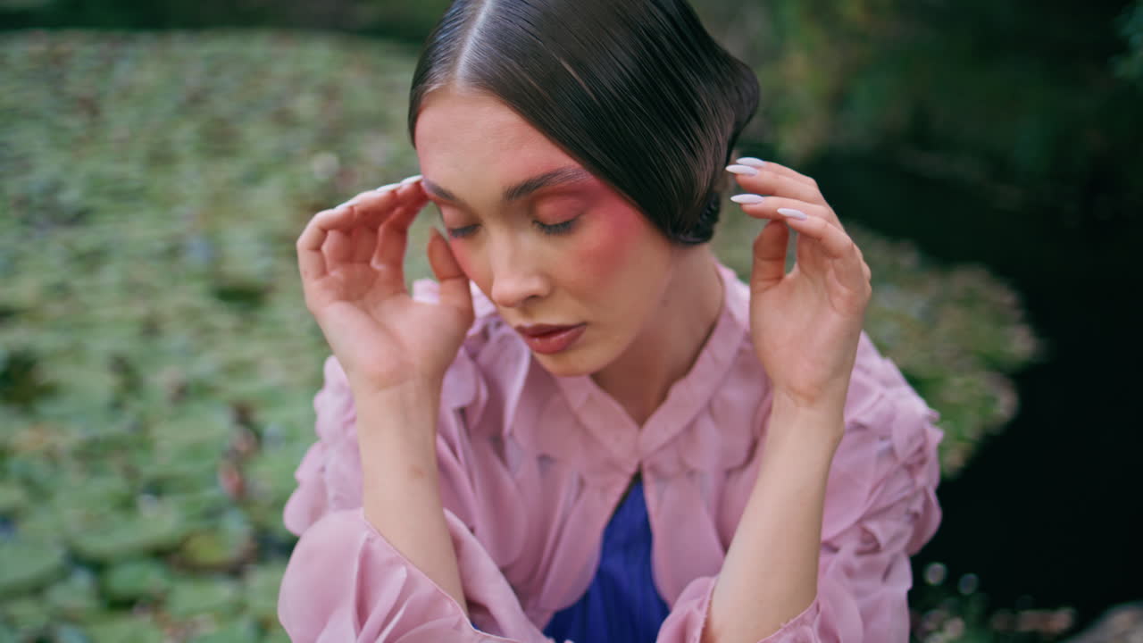 hermosa niña de cuento de hadas sentada en el tranquilo estanque del bosque con lirios de agua de cerca.