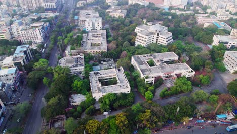 jntu university with trees and road at kphb, hyderabad, telangana, india. day time, moving up, drone shot, 4k.