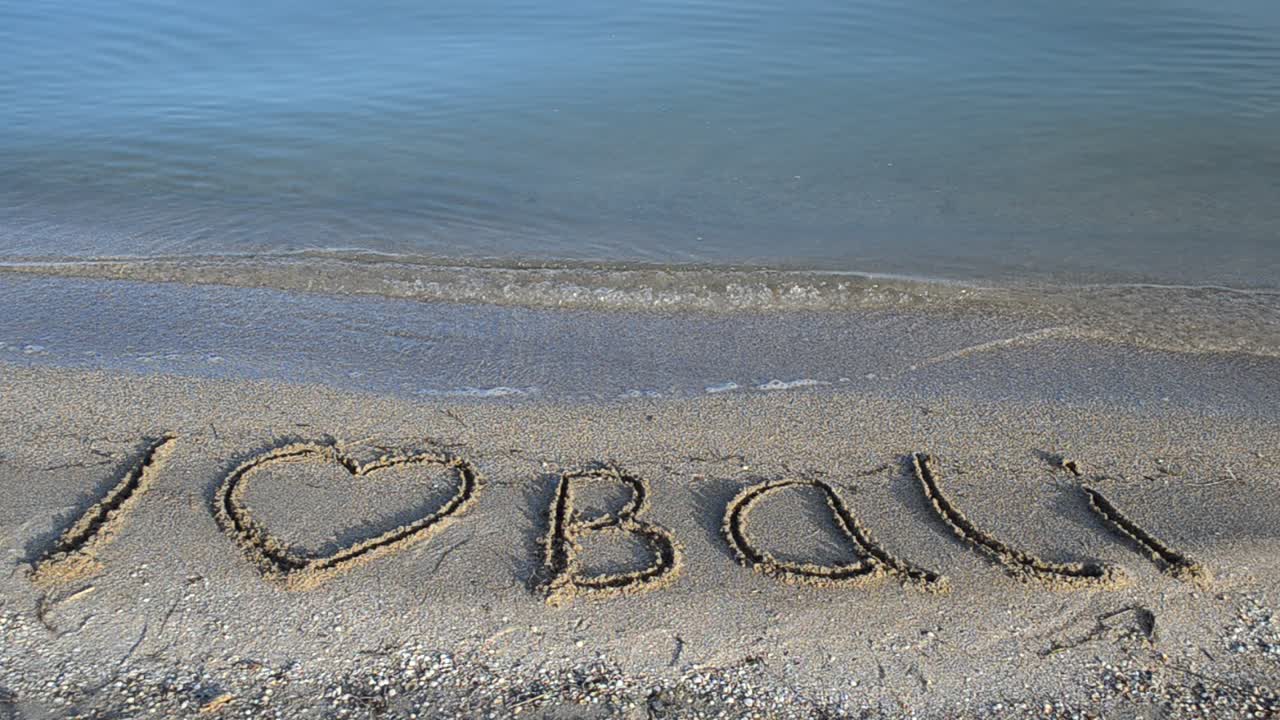 Inscription "I love Bali" writing on the sand. Inscription on sand, the beach