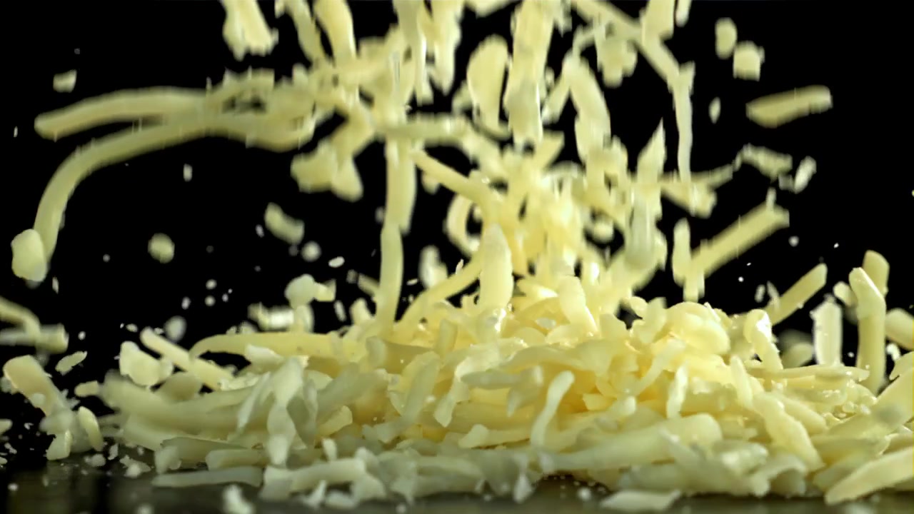 Formaggio grattugiato che cade su una superficie nera al rallentatore