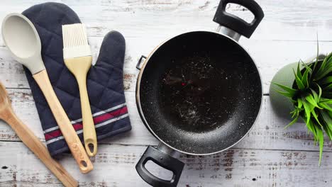 a black pan with cooking utensils on a white wooden table