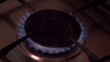 a stove burner with the gas lit and making a circle with a blue flame