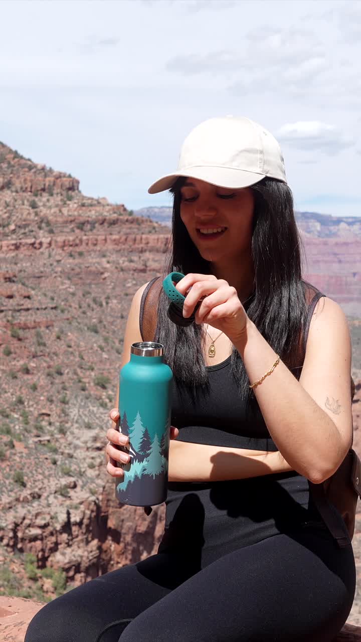 Mujer joven bebiendo agua de una botella mientras hace senderismo en el Gran Cañón