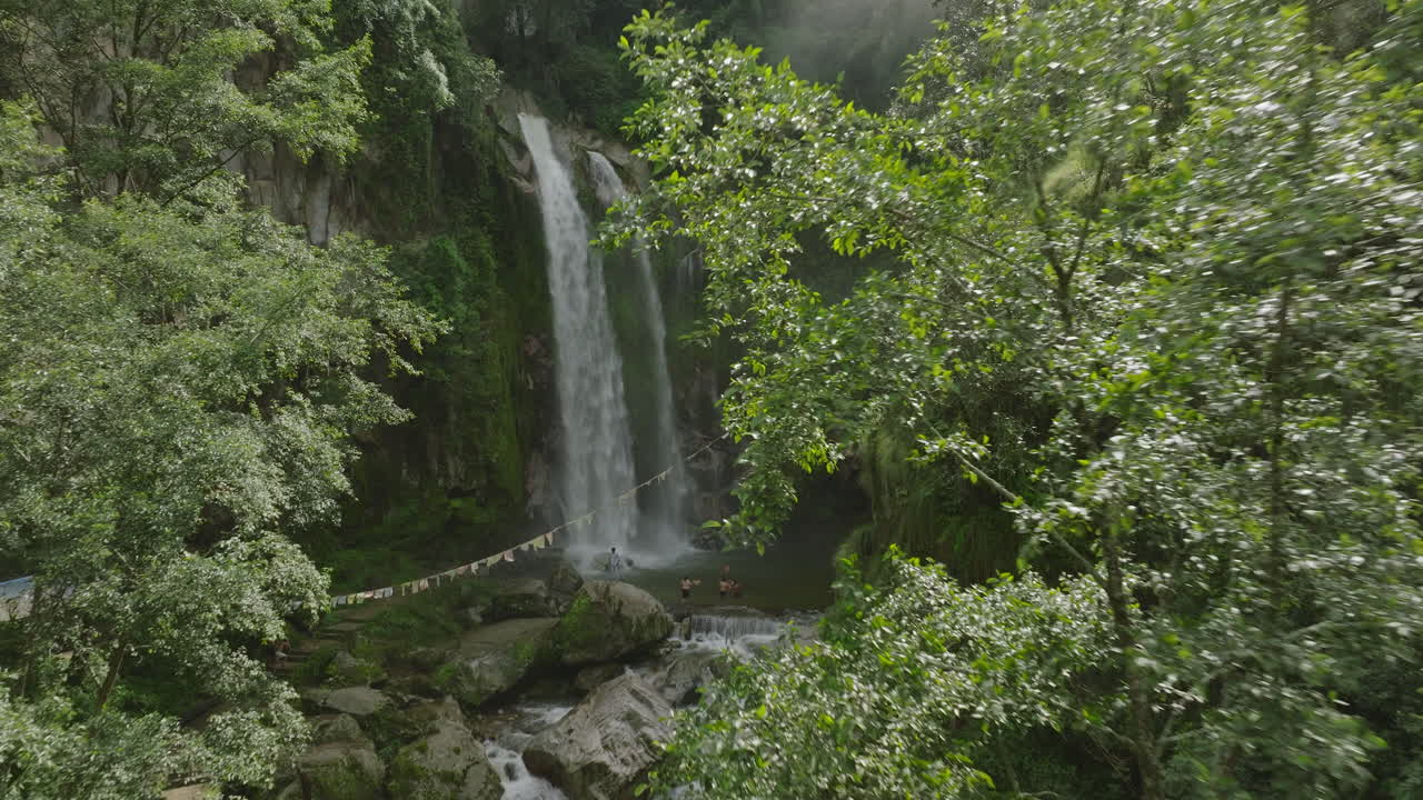 Drone shot of a stunning waterfall in Nepal, nestled in a lush forest. The misty monsoon scene adds to its beauty, making it a must-visit tourism spot for nature lovers and adventure seekers.
