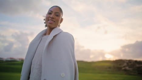 romantic woman walking meadow at cloudy sky. smiling african american resting